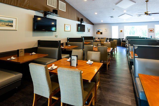 A restaurant with tables and chairs and a tv on the wall
