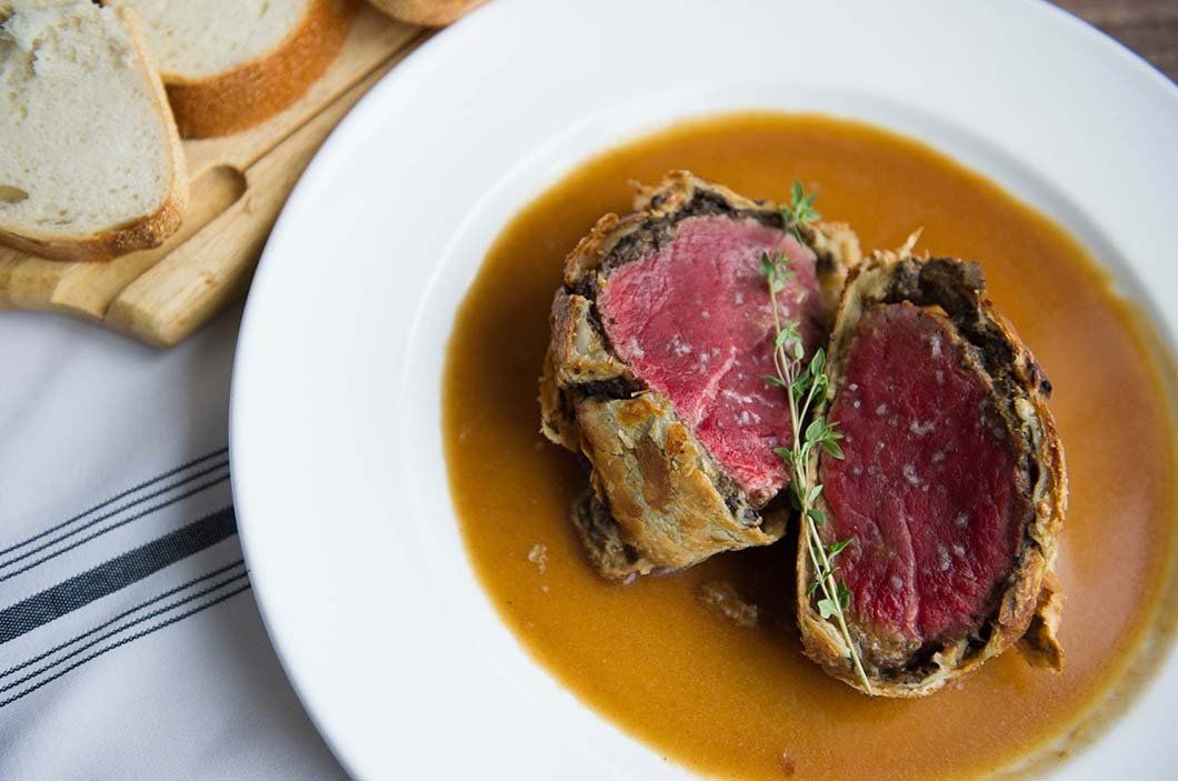 A white plate topped with a piece of meat and sauce.