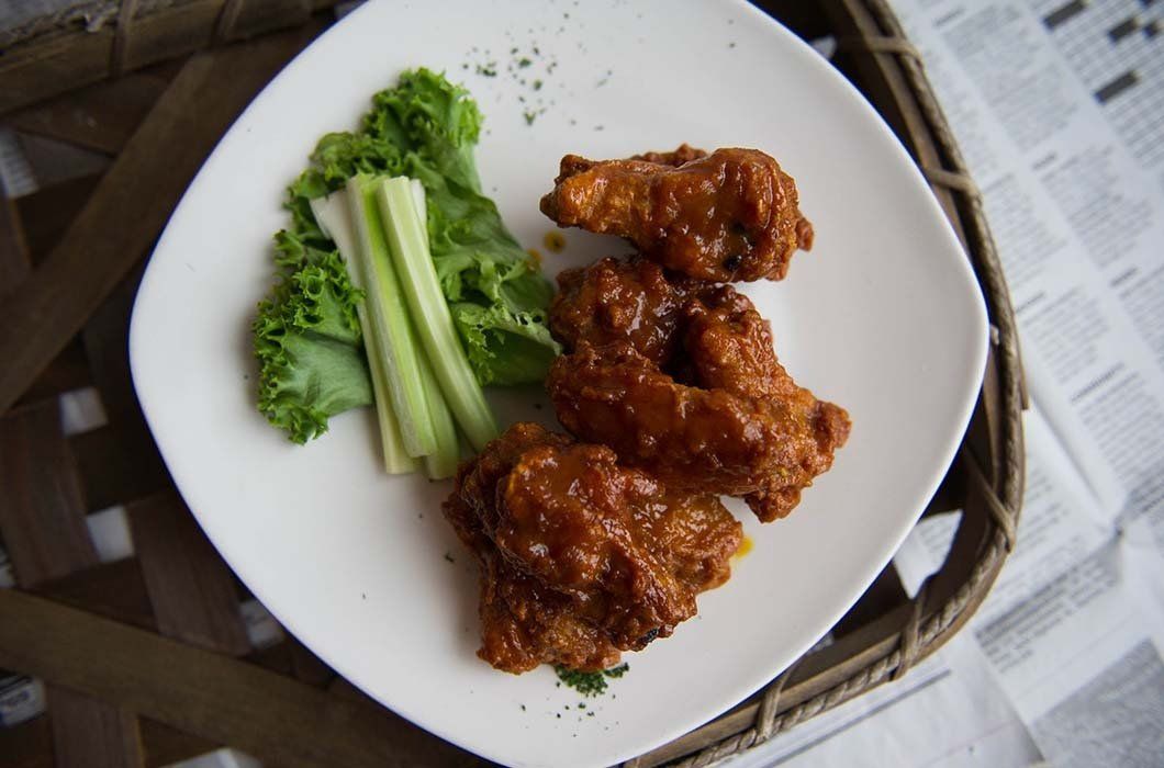 A white plate topped with chicken wings and celery sticks.