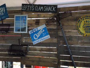 A sign for lefty 's clam shack hangs on a wooden wall