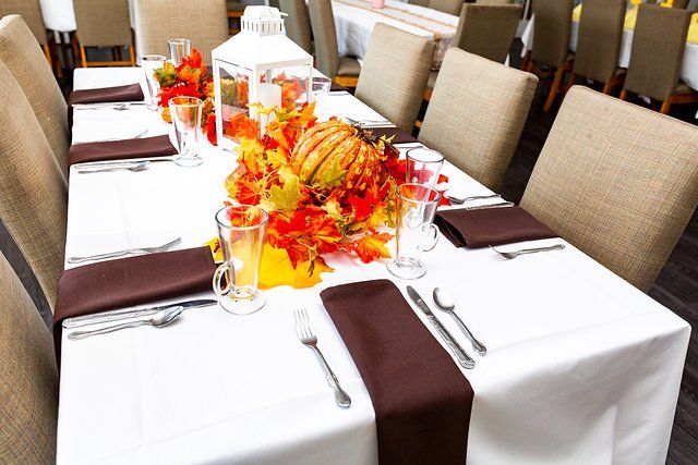 A long table with a white table cloth and brown napkins