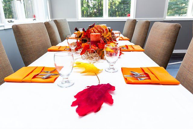 A long table with a centerpiece of leaves and a candle on it