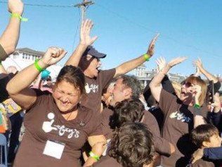 A group of people wearing i-guys shirts are raising their arms in the air.