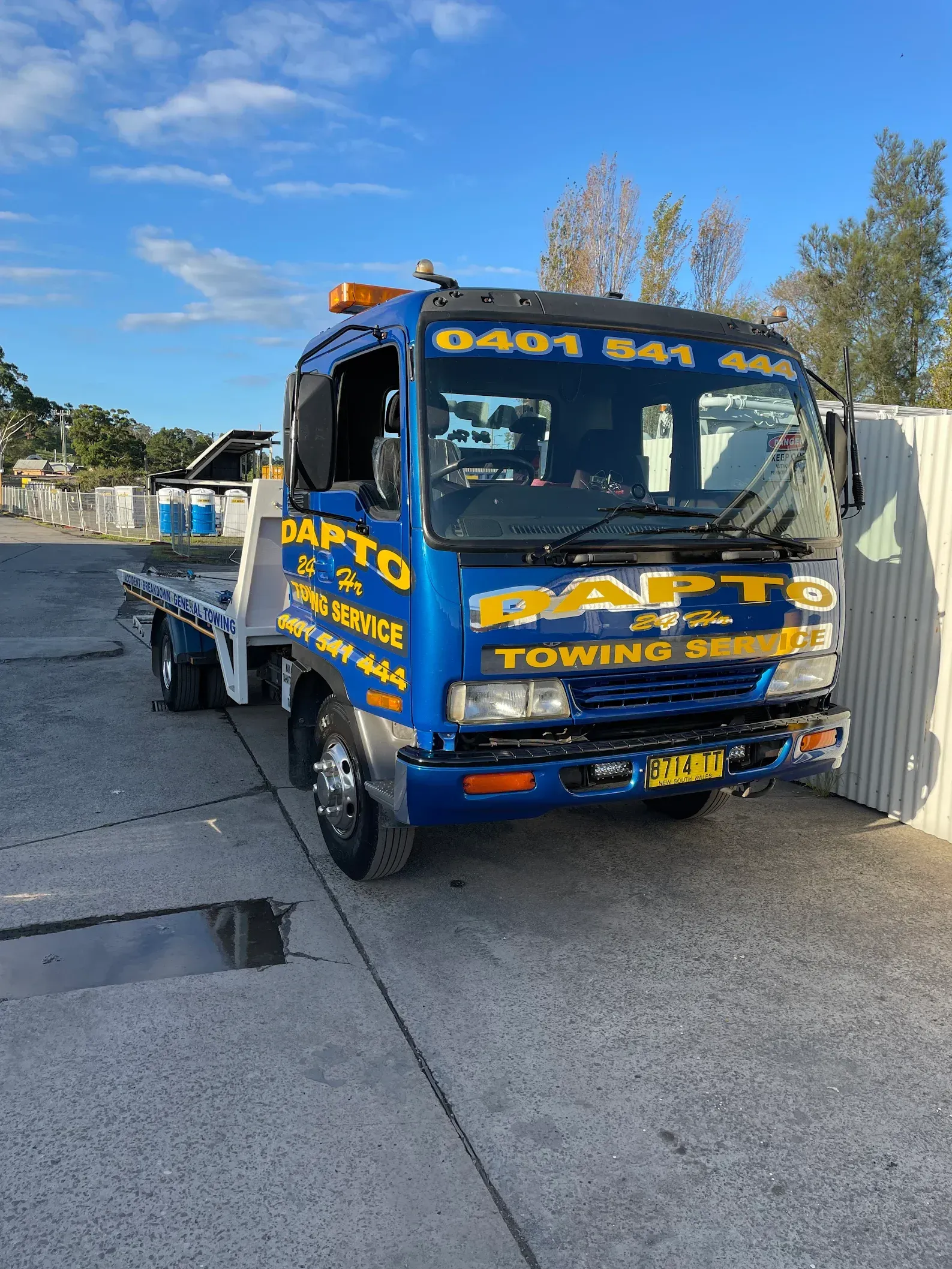 A blue and yellow tow truck is parked on the side of the road.