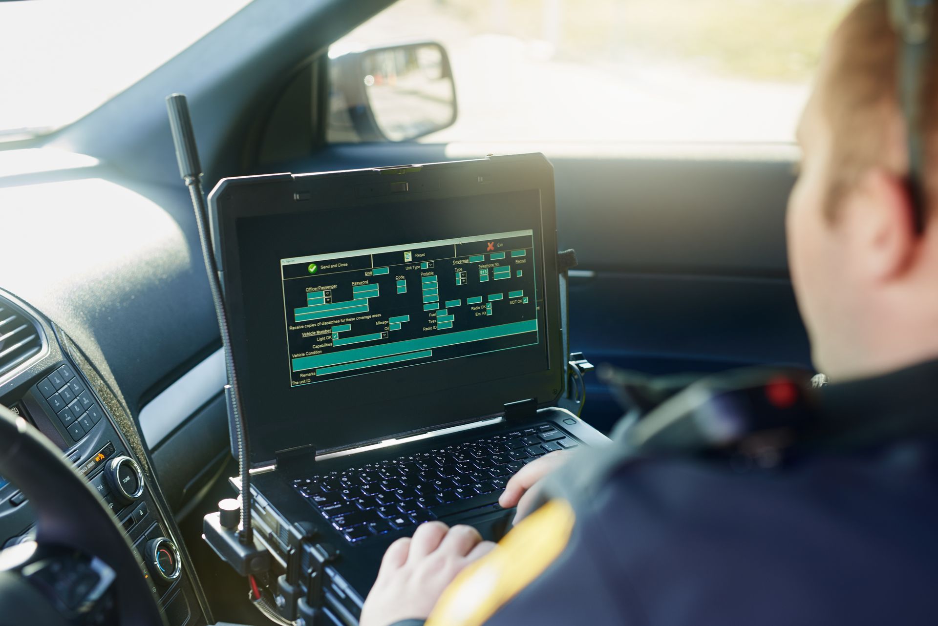 A police officer is typing on a laptop in a car