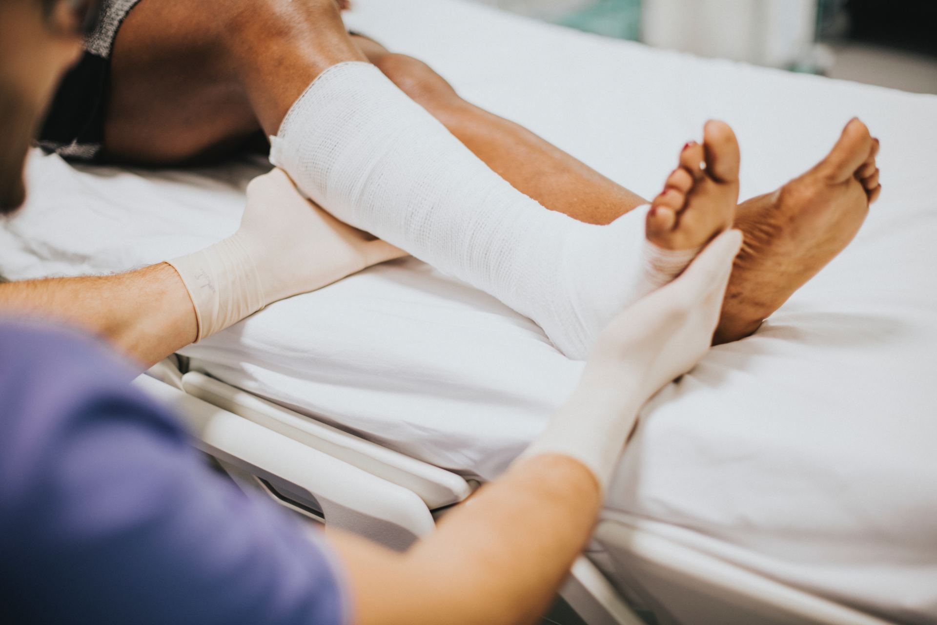 A person is laying in a hospital bed with a cast on their leg.