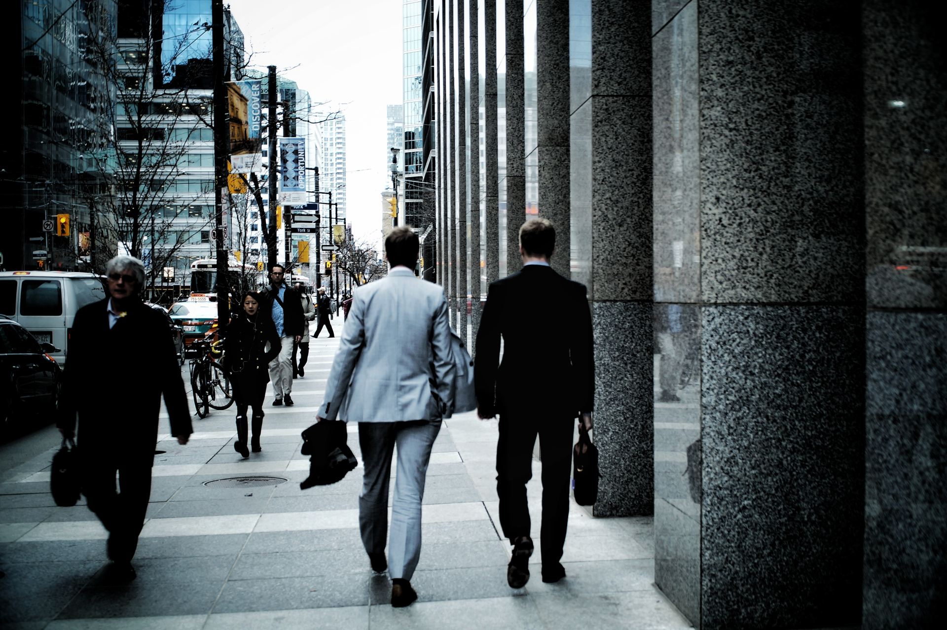 Three men in suits are walking down a city street