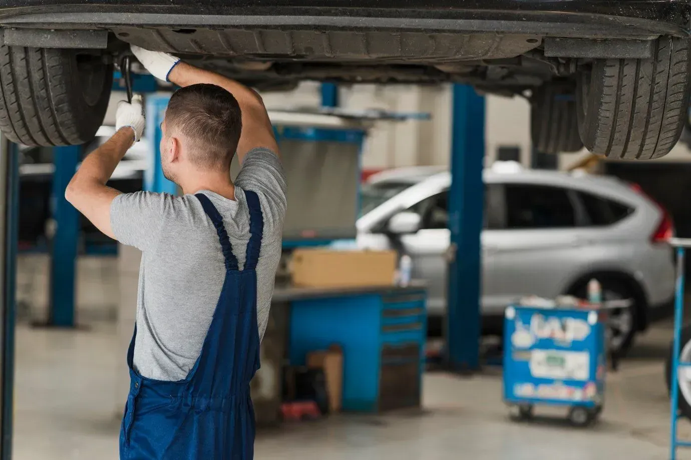 A man is working under a car in a garage in Los Angeles, CA