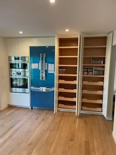 Kitchen with stainless steel appliances, blue refrigerator, and white pantry cabinets with pull-out drawers.