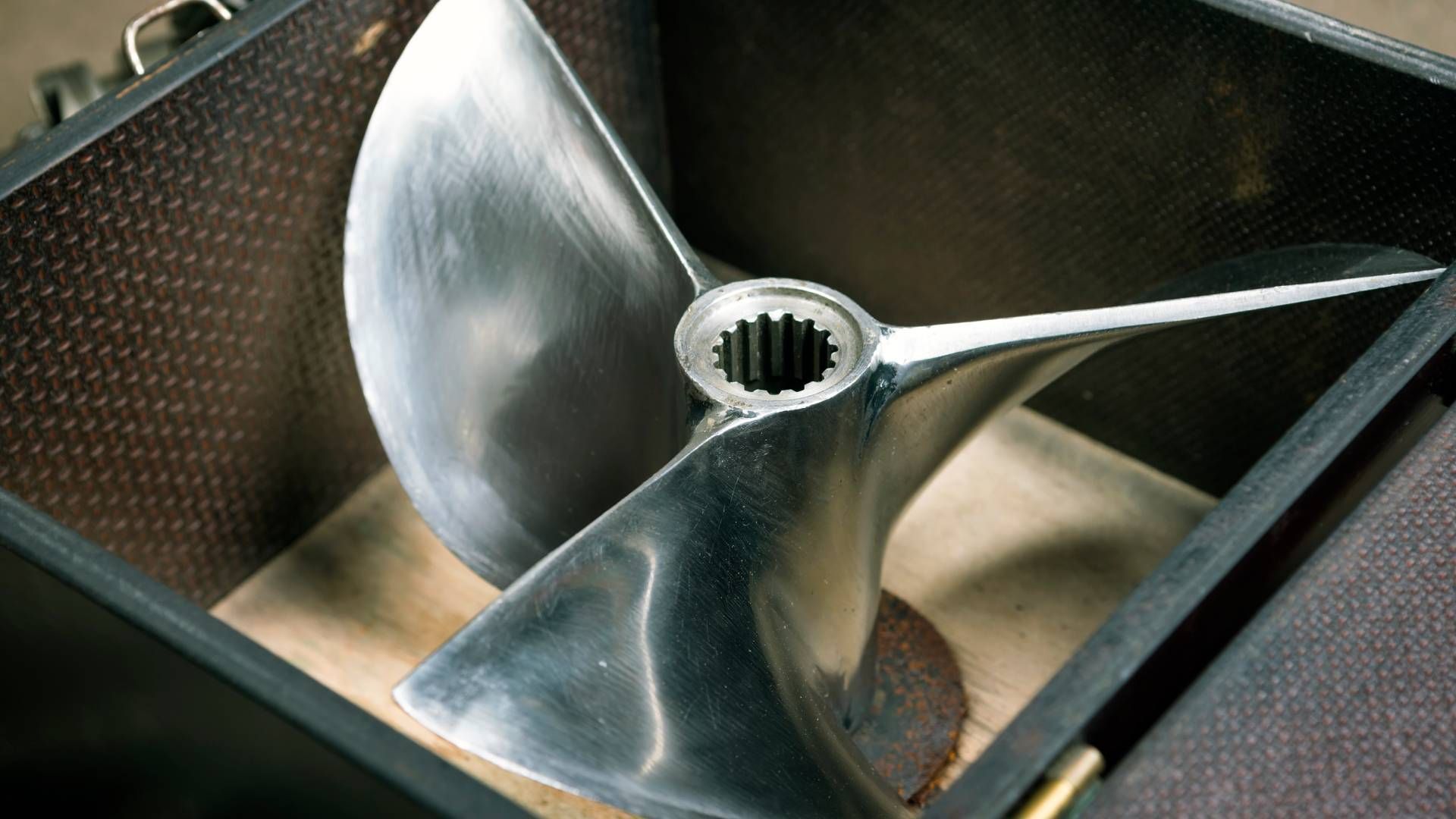 Boat propeller in a wooden box. Shiny metal, three blades.