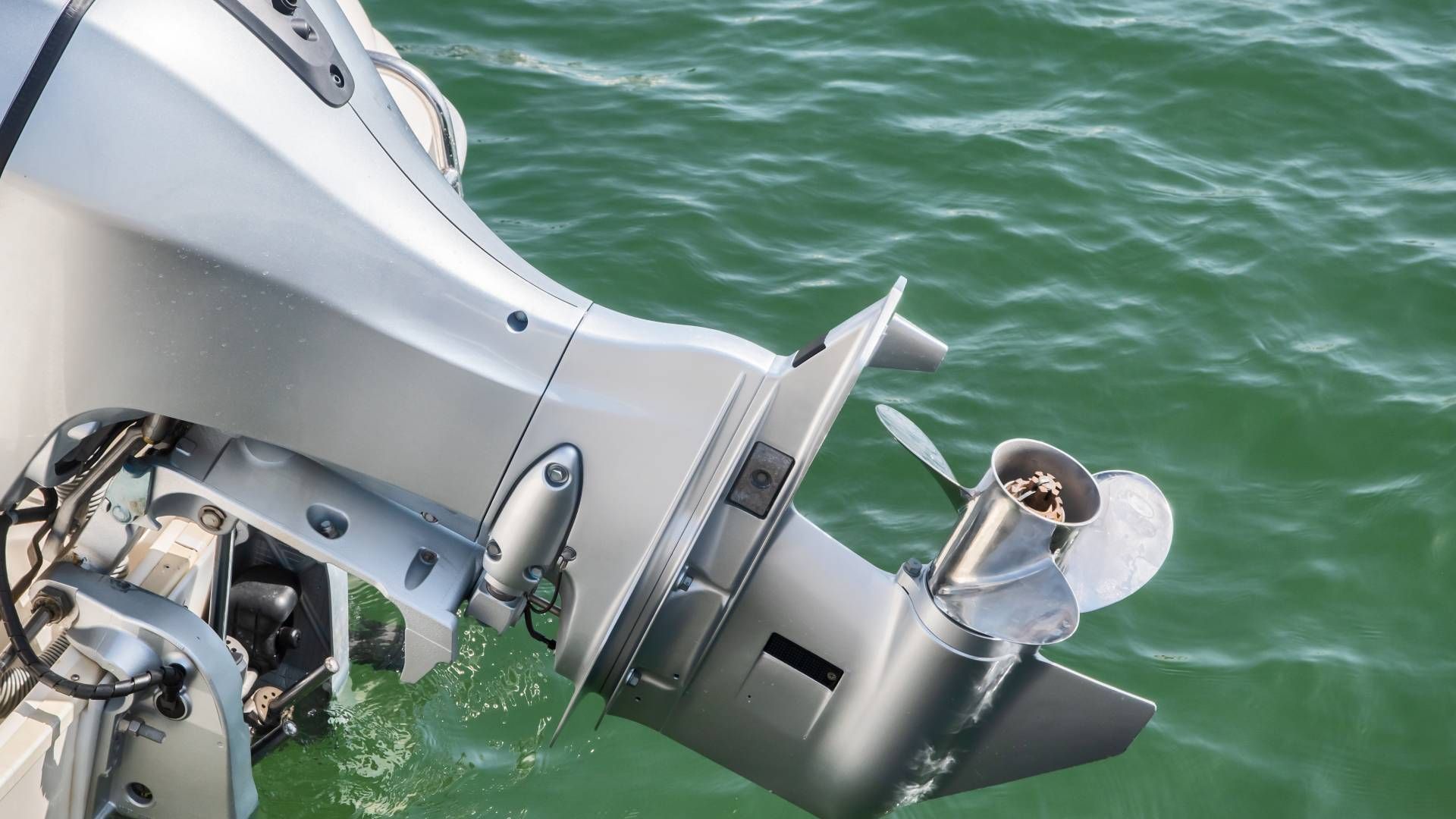 Silver outboard motor in green water.