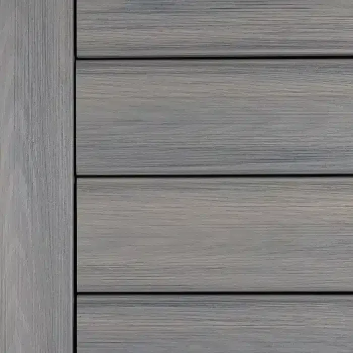 Gray composite wood siding, close-up. Textured planks with vertical accent trim on the left.