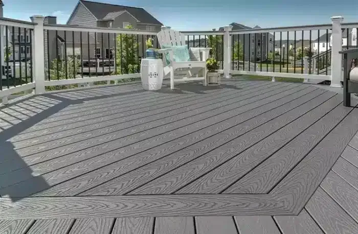 Gray composite deck with white railing, a white chair, and cityscape background.