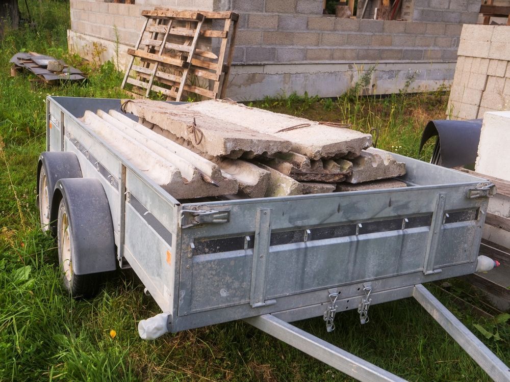 A Trailer Filled With Concrete Blocks is Parked in the Grass — Marshall Notaras Hardwoods Pty Ltd In Armidale, NSW