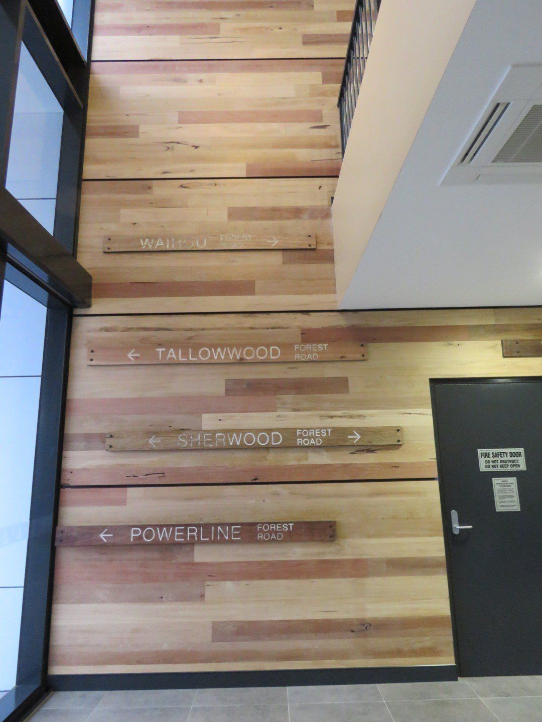 A Wooden Wall With Directional Signs on It — Marshall Notaras Hardwoods Pty Ltd In Ballina, NSW