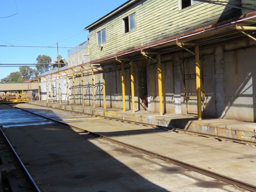A Train Station With a Green Building and Yellow Poles — Marshall Notaras Hardwoods Pty Ltd In Tamworth, NSW
