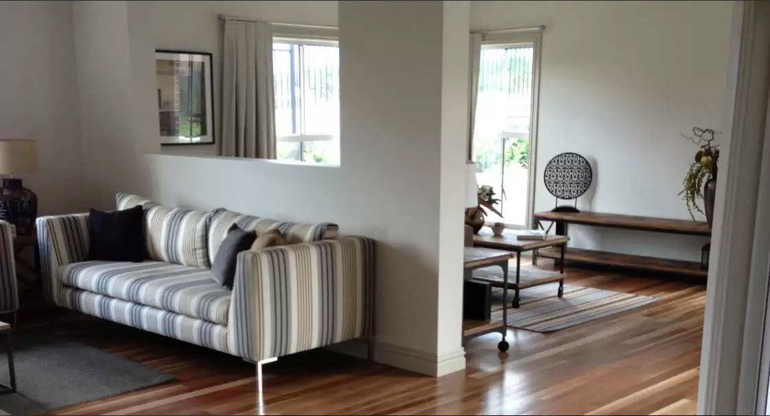 A Living Room With a Striped Couch and a Wooden Floor — Marshall Notaras Hardwoods Pty Ltd In Melbourne, VIC
