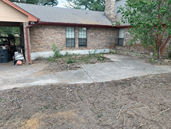 A brick house with a concrete driveway in front of it.