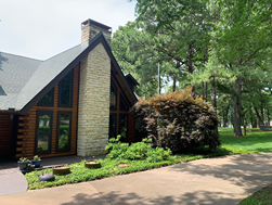A large house with a lot of windows is surrounded by trees and grass.