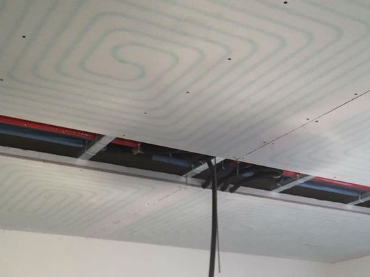 delle tubature visibili da un soffitto con dei pannelli non ancora finito