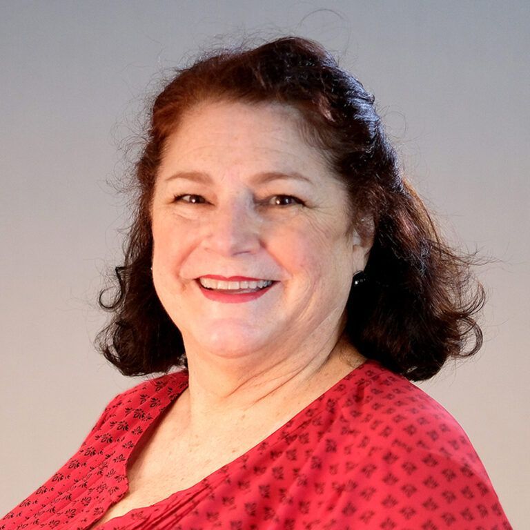 A woman in a red shirt is smiling for the camera