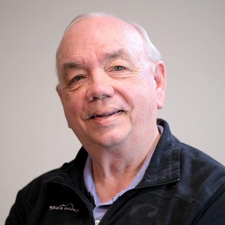 A man wearing a black jacket is smiling for the camera.