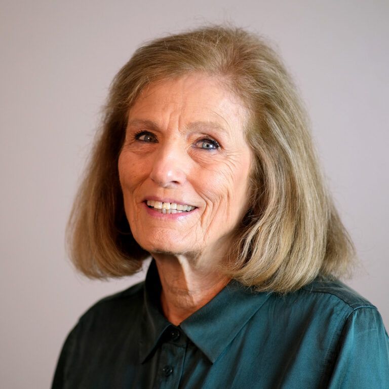 A woman in a green shirt is smiling for the camera.