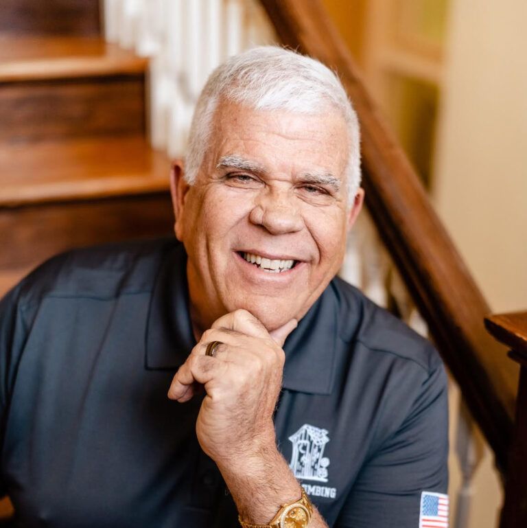A man in a black shirt with an american flag on his arm is smiling