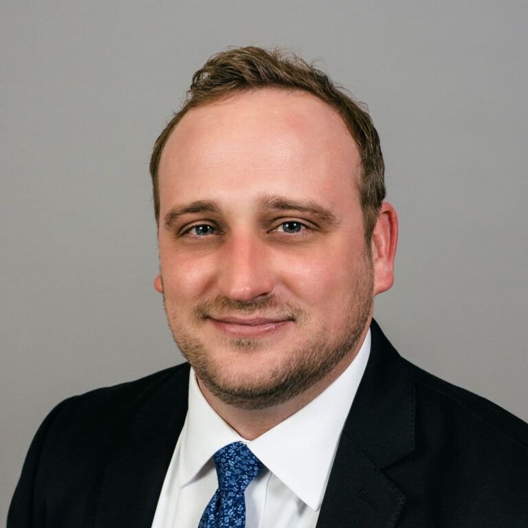 A man in a suit and tie is smiling for the camera.