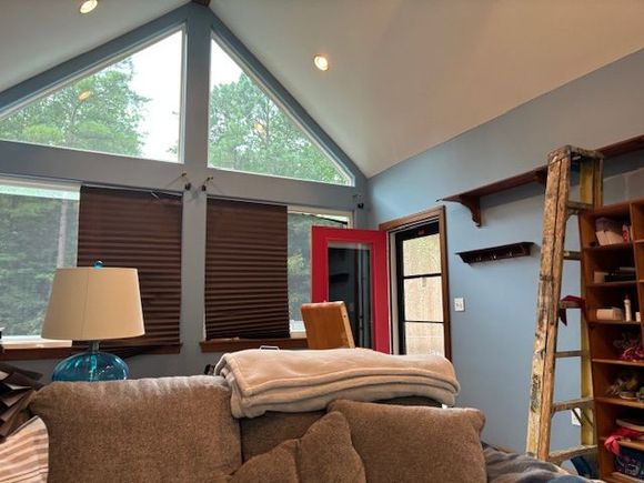 A living room with blue walls, a red door, large windows, and a brown couch.