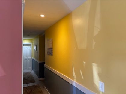 Hallway with yellow upper walls, gray lower walls, white trim, and a white door at the end.