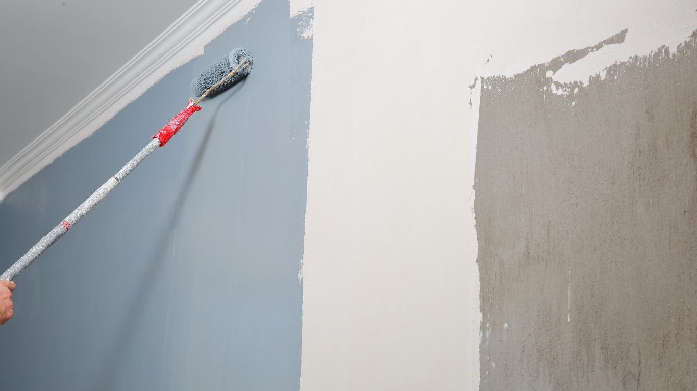 A person using a roller to apply black waterproof coating on a rooftop.