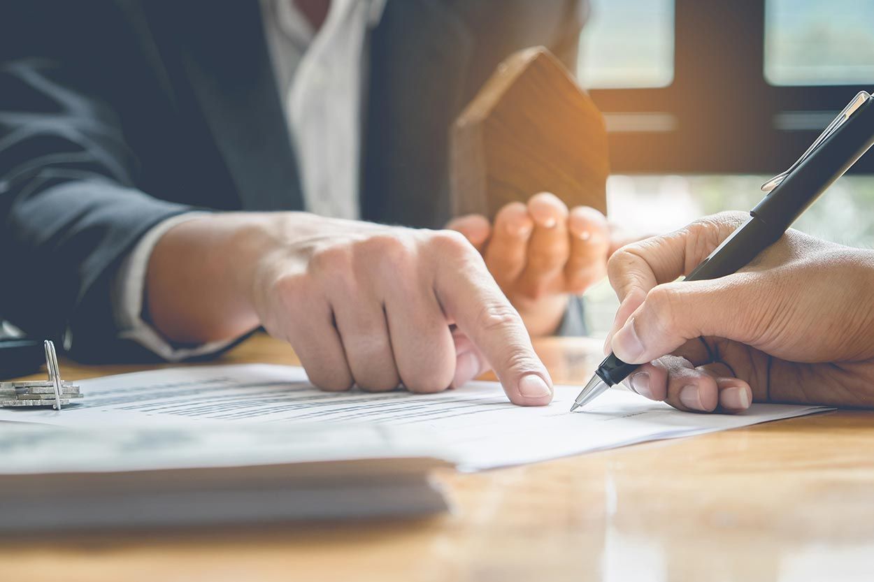 A couple of people are sitting at a table signing a document.