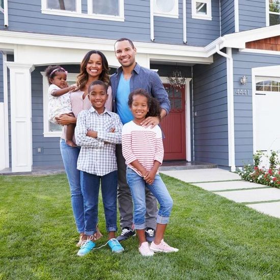 A family is posing for a picture in front of their house.