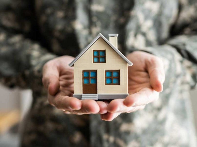 A soldier is holding a small model house in his hands.