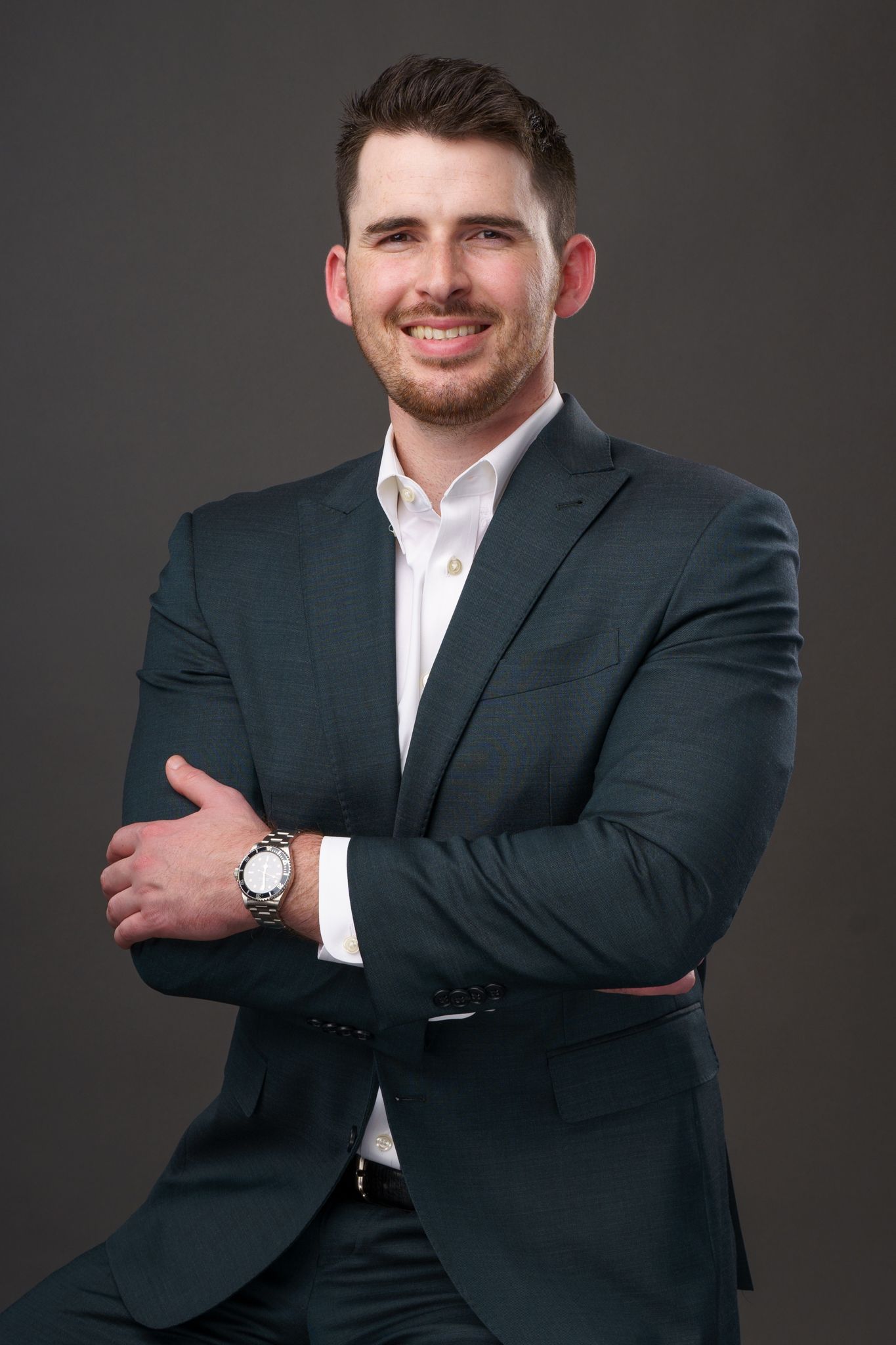 A man with a beard is wearing a suit and smiling for the camera.