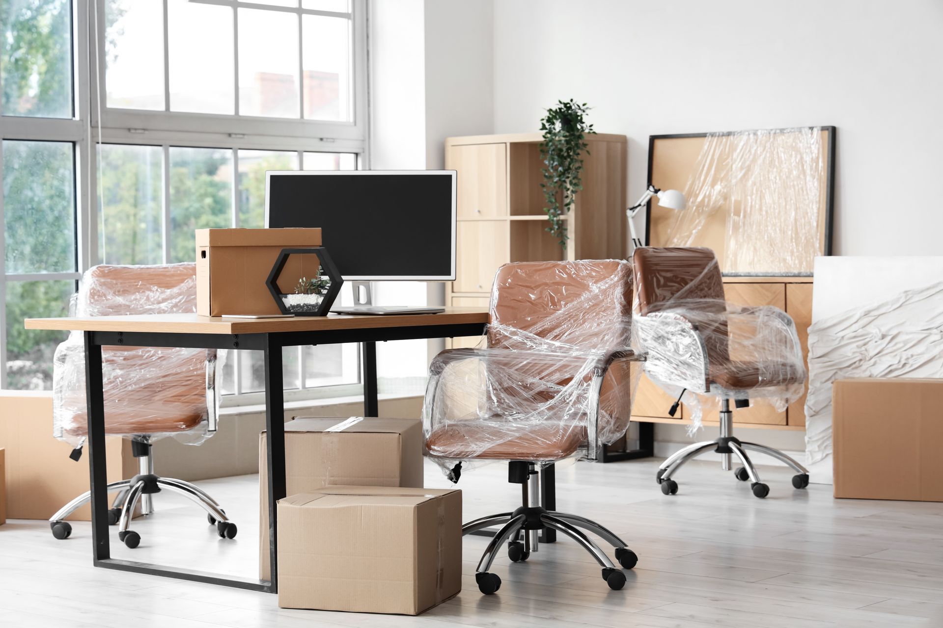 Office furniture and boxes wrapped in plastic during a move.