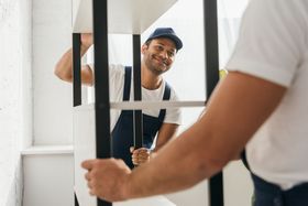 two men are moving a shelf in a room .