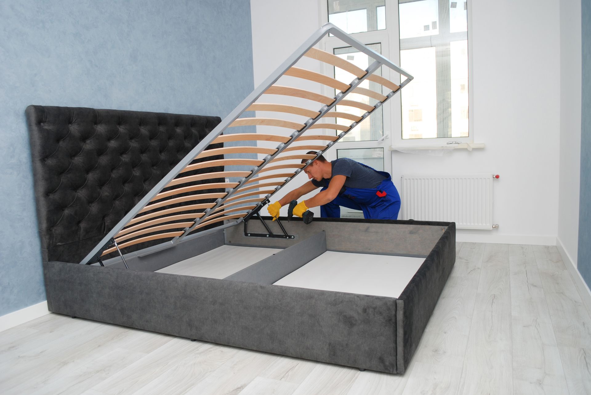 a man is working on a bed frame in a bedroom .