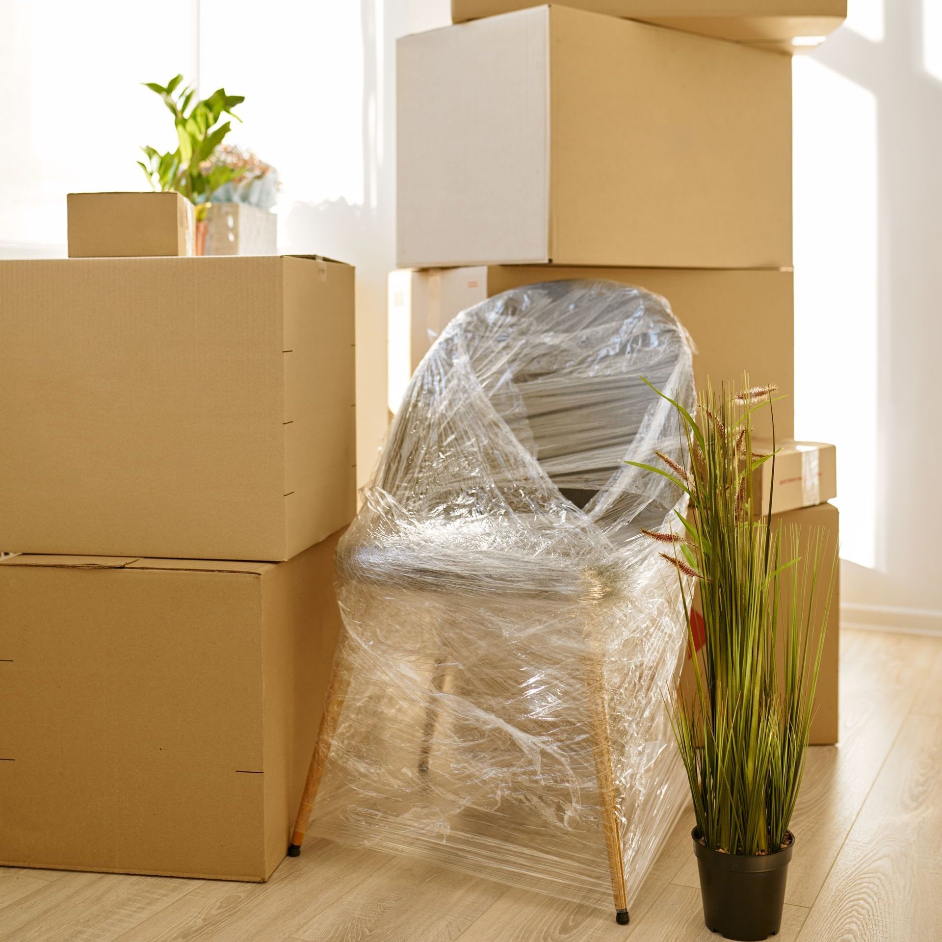 a chair wrapped in plastic is sitting in front of a pile of cardboard boxes .