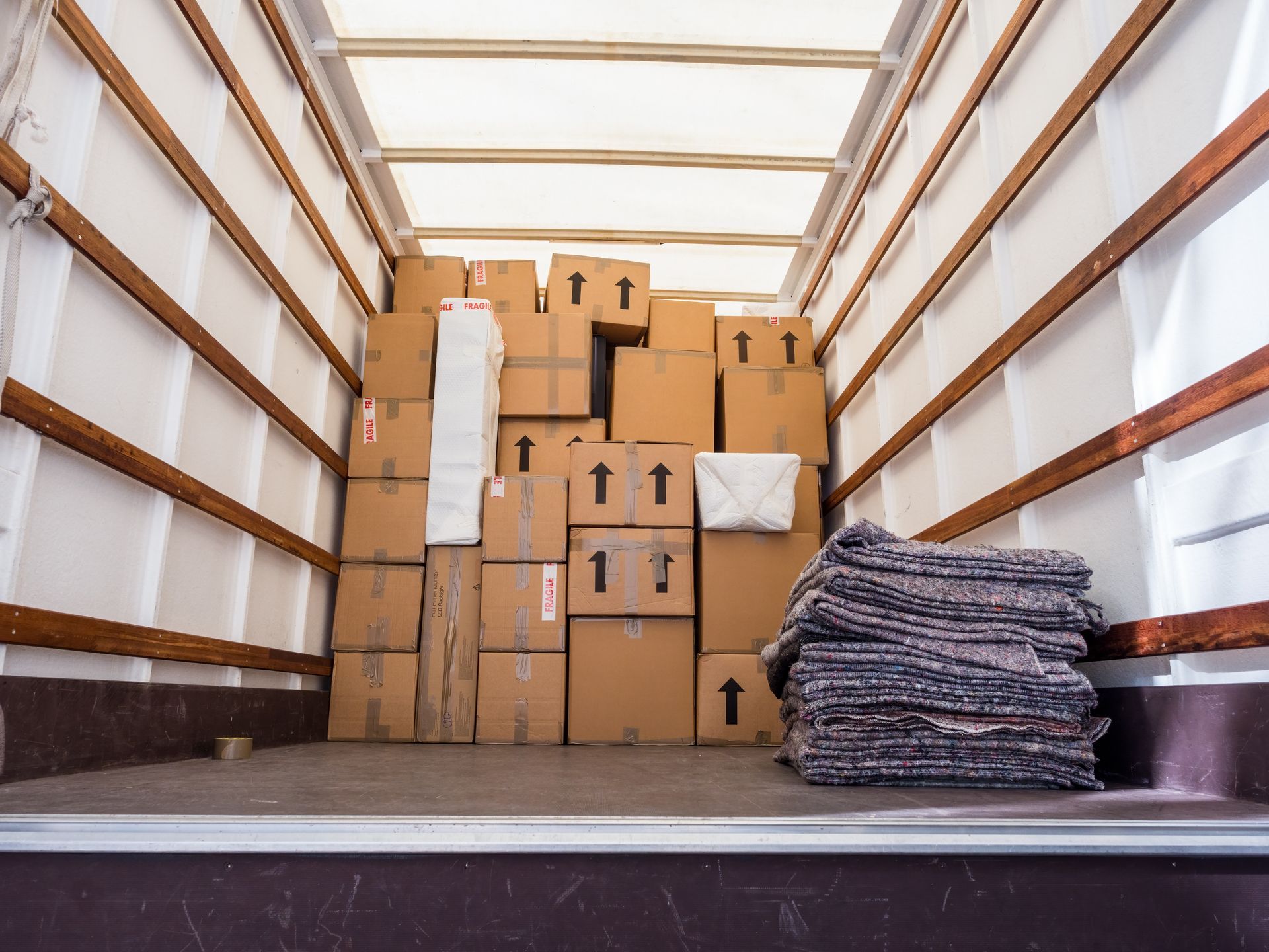 the inside of a moving truck filled with boxes and blankets .