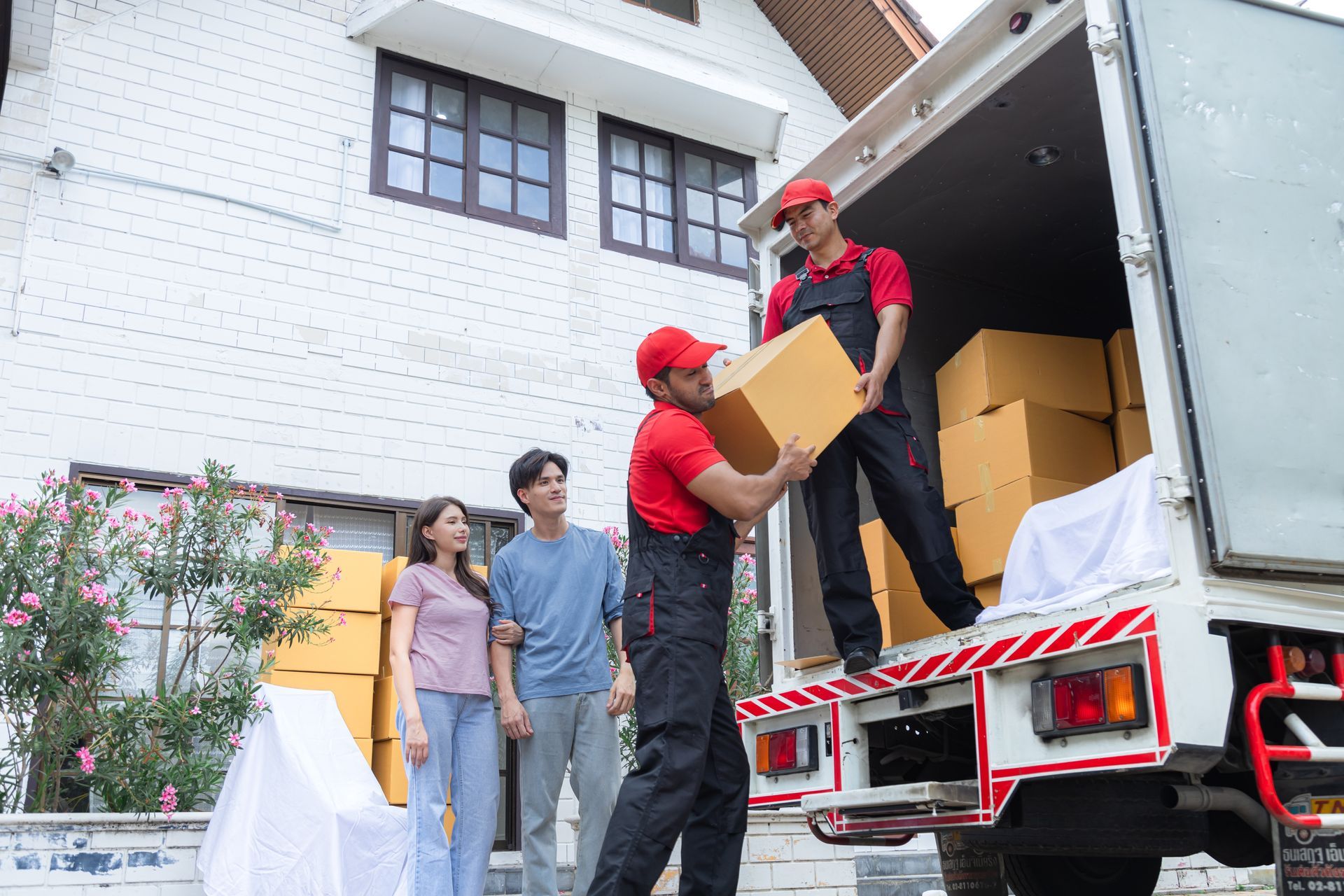 a group of movers are loading boxes into a truck .