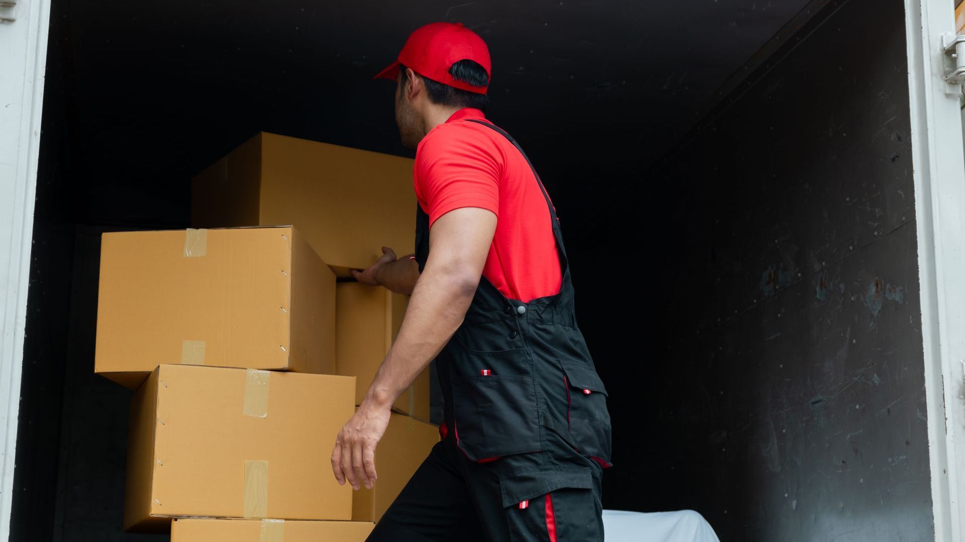 a delivery man is loading boxes into a truck .