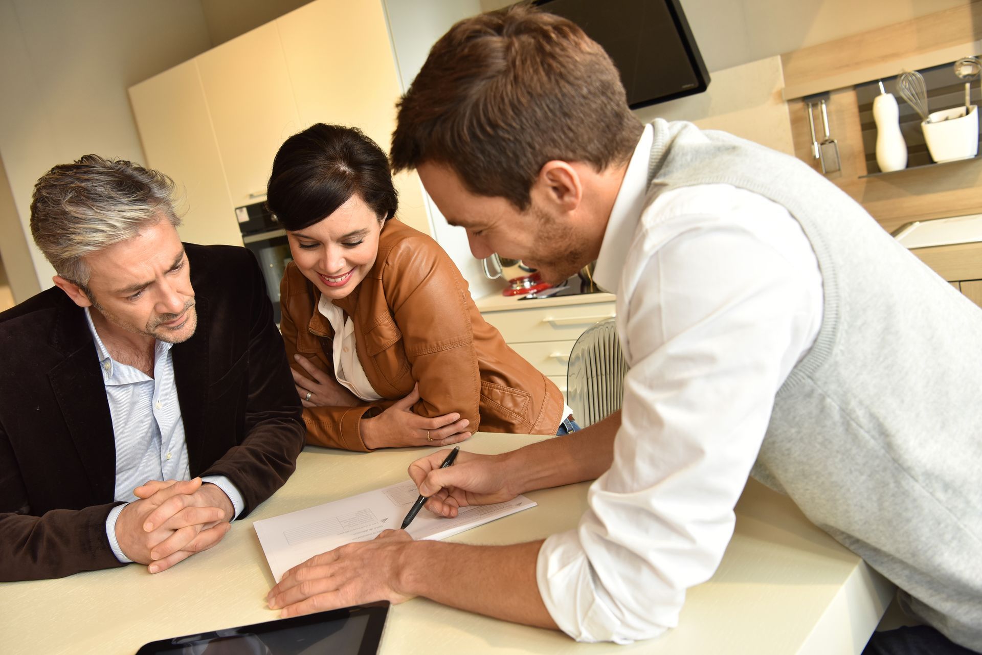 a man and a woman are sitting at a table looking at a tablet .
