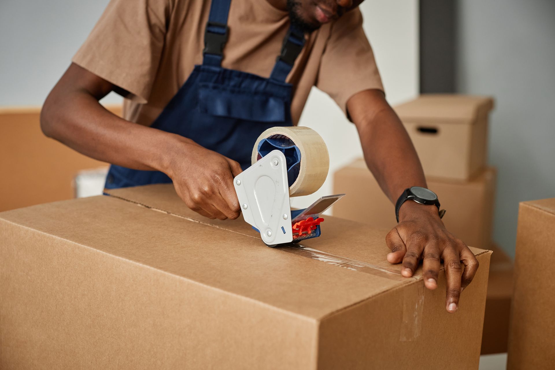 Close-up of someone sealing a cardboard box with packing tape.