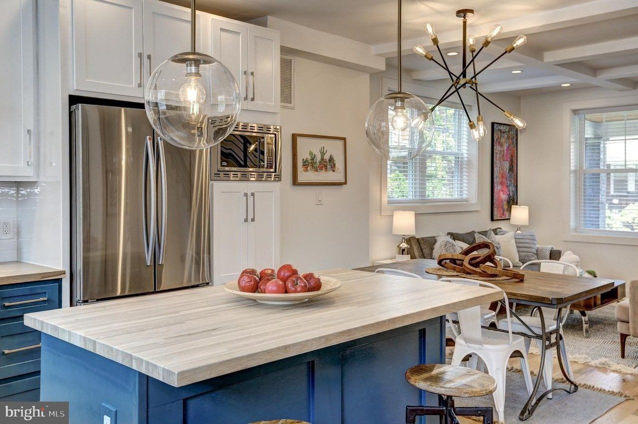 a kitchen with a blue island , stainless steel appliances , white cabinets and a stainless steel refrigerator .