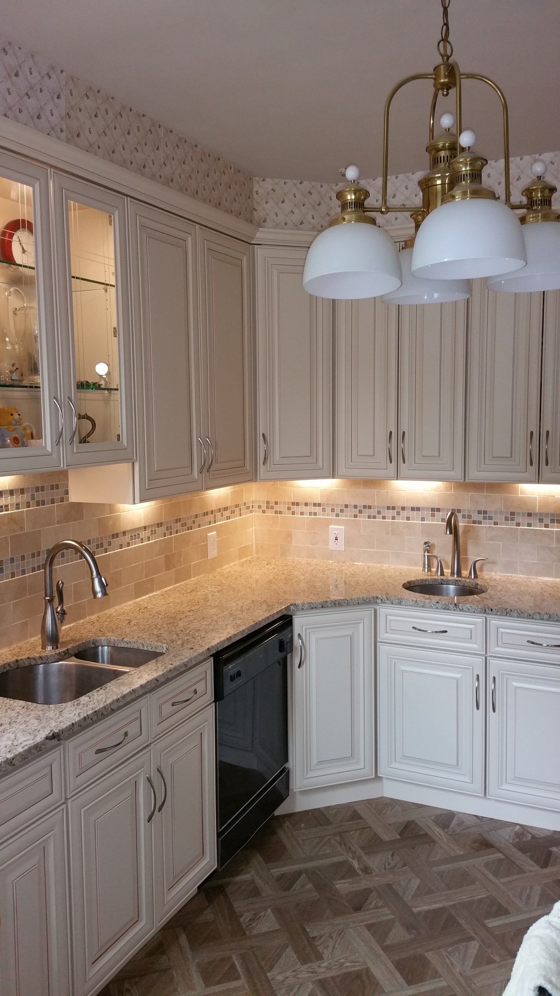 a kitchen with white cabinets , granite counter tops , a sink and a dishwasher .