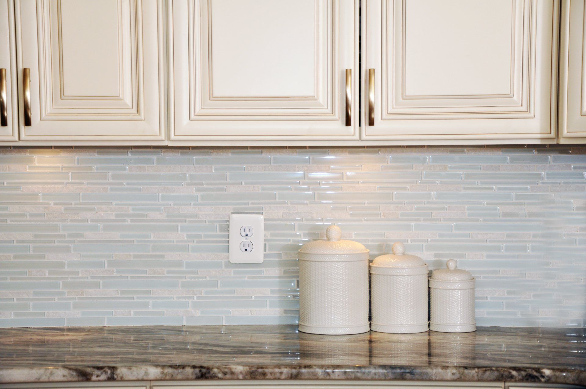 a kitchen counter with three white canisters on it .