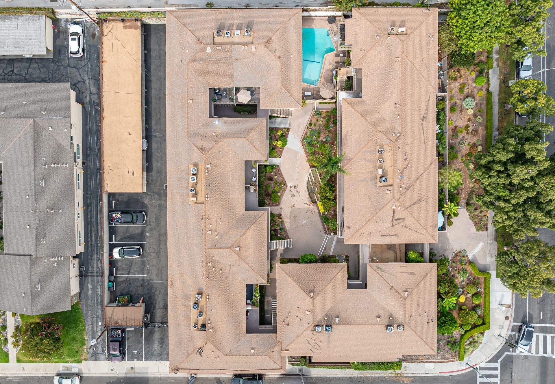 Aerial view of a U-shaped apartment complex with a central courtyard, pool, and surrounding parking area.