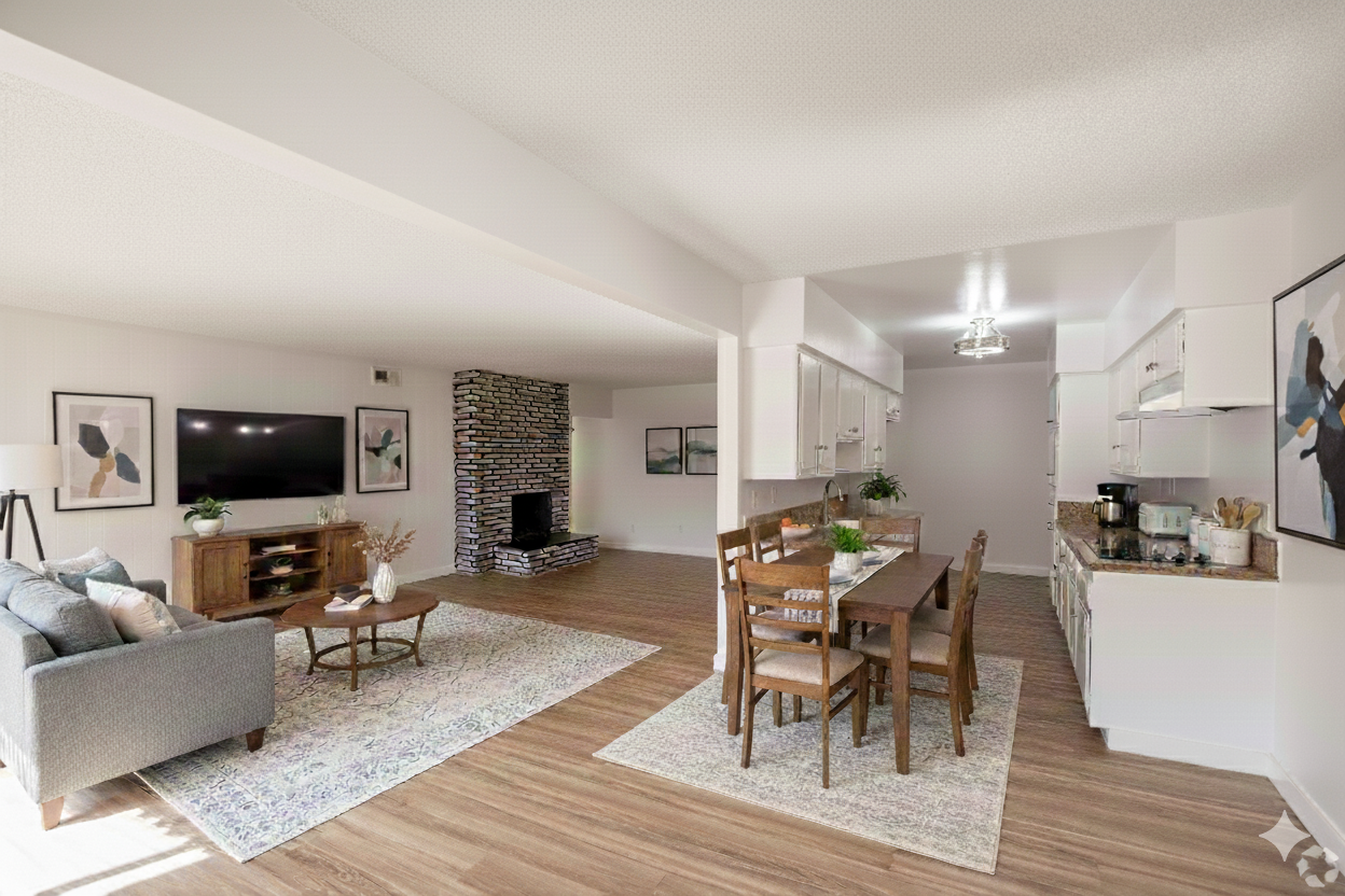 A bright, open-plan living room and dining area with a stone fireplace, wood floors, and neutral modern furniture.